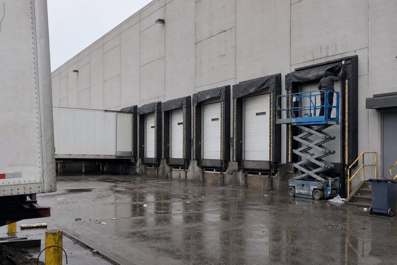 Technician on a lift at a row of loading dock doors